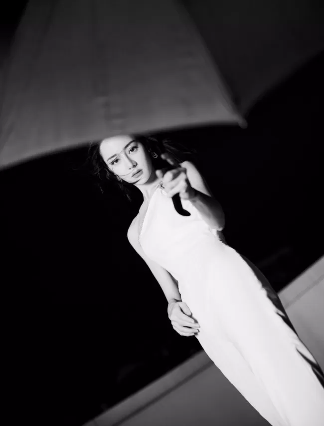 热巴穿斜肩连体裤撑黑伞 眼神霸气酷飒十足